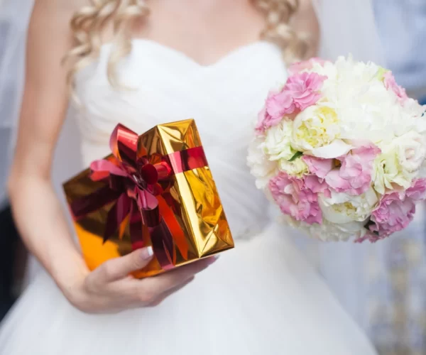 stock-photo-stylish-elegant-happy-blonde-bride-in-amazing-dress-with-bouquet-of-roses-and-a-gift-box-329638439-transformed-3514684823-e1686002708582
